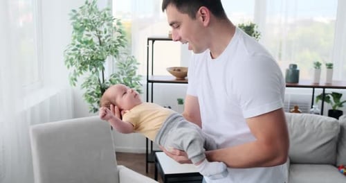 Father Cradling Infant in Bright Home
