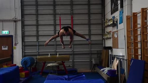 a Still shot of a guy working out on the still rings
a gymnastics apparatus that is extremely hard
i