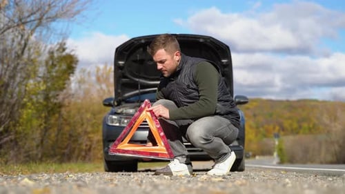 Young Man Puts It a Red Triangle to Warn Other Road Users Car Breakdown or Engine Failure Stop at