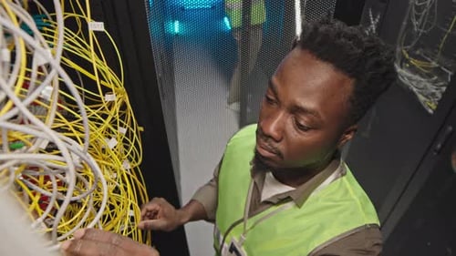 Black System Administrator Connecting Wires in Server Room