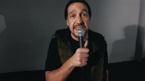 Man Singing Passionately Into a Microphone on Stage