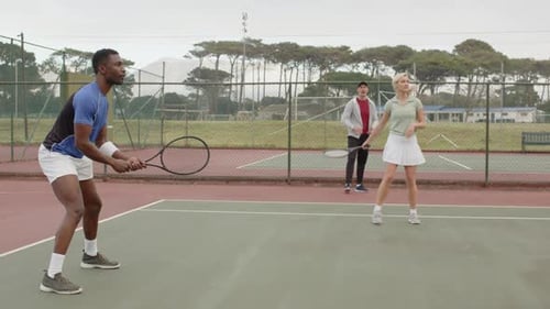 Entraîneur alimentant la balle et guidant divers joueurs de tennis échangeant des coups droits le long de la ligne de fond pendant l'exercice