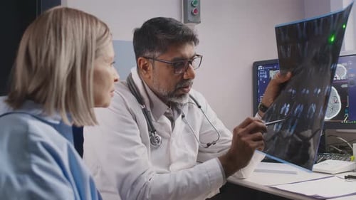 Indischer Chirurg zeigt Röntgenbild und erklärt Frau die Diagnose