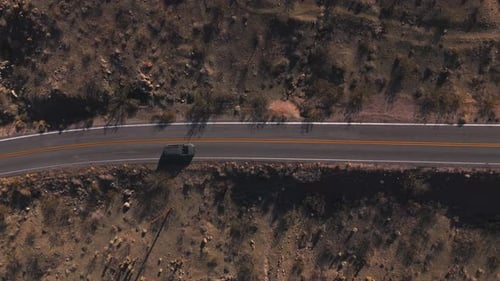 Van Driving Along Winding Desert Road. Aerial View Following Vehicle Through Sunny Nevada Desert.