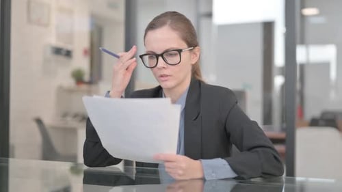 Woman Reading Documents at Desk in Modern Office