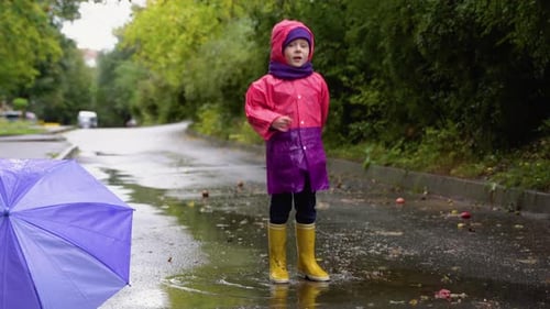 Children with Umbrella and Rain Boots Play Outdoors in Heavy Rain