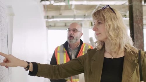 Construction foreman and owner discuss plans on wall in Canada office