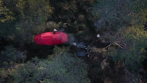 Campsite In The Forest. Camping Tent With A Man Sitting By The Bonfire At Daytime. top-down