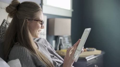 Woman Relaxing in Bed Using Tablet Device
