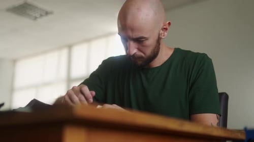 Professional Leather Craftsman at Work Table Making Stitching Holes in Black Handbag with Leather