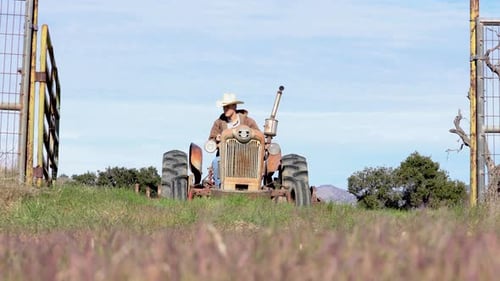 Rancher Towing Harrow Through Fence on Farming Field