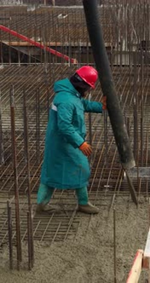 Construction Worker Pouring Concrete with Pump Hose into Reinforced Foundation Vertical Video