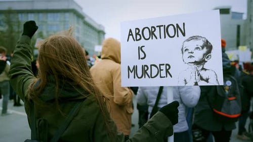 People Marching Through City with Signs