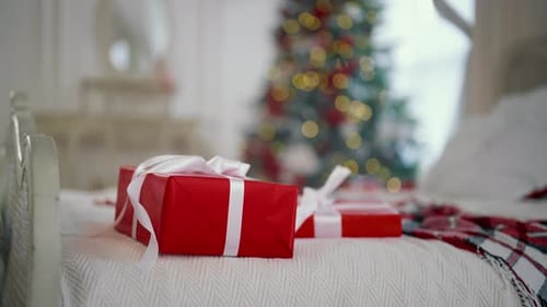 Christmas Gifts in Red Paper with White Ribbons Lying on Bed in Cozy Room Merry Xmas and Happy New