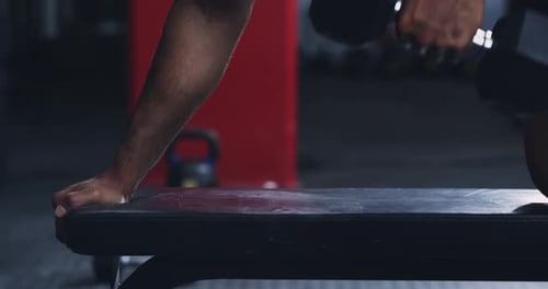 Man Doing Dumbbell Row Exercise on Bench in Gym