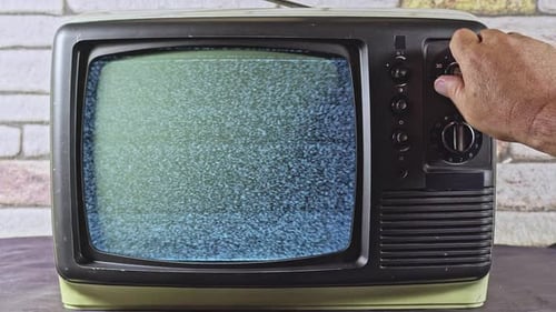 Hand Turns Channel Knob on Retro Television