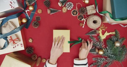Top view of girl hands unpacking present gift box winter christmas decorations on red background.