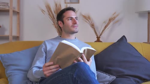 Young Man Reading Book on Sofa