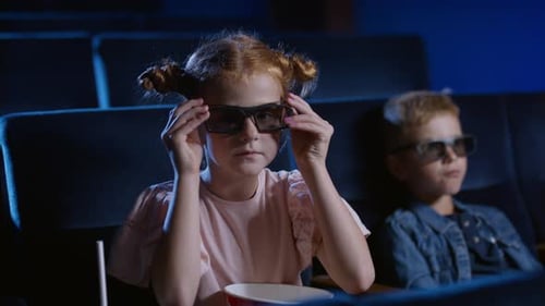 Cheerful small children with 3d glasses enjoying a film at the cinema girl smiles