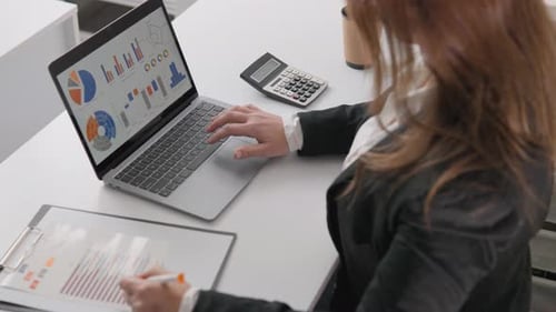 Businesswoman Analyzing Charts at Her Desk