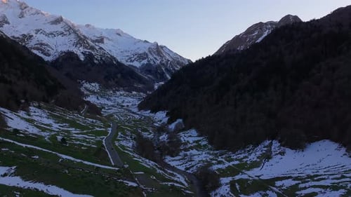 Snowy Pyrenees Mountains with Winding Road at Sunset