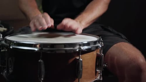 Die Hand eines Schlagzeugers schlägt auf eine Snare Drum und erzeugt einen scharfen und unverwechselbaren Klang. Die Trommel ist aus Holz mit