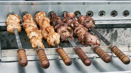 Cooking Pork and Chicken Meat on Skewers in an Electric Barbecue Kebab Maker Street Food Concept