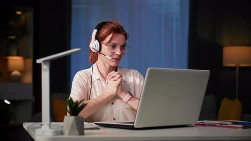 Home Office Young Woman in Glasses Communicates Online Using a Headset and Video Communication on a