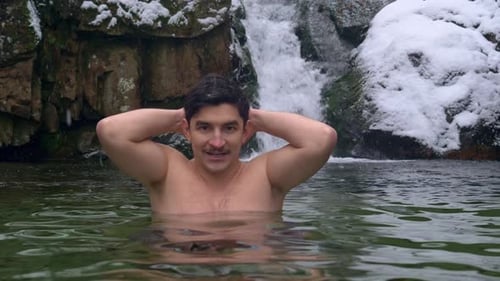 Man in Cold Water Near Waterfall in Winter