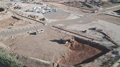 Excavator and Trucks Working on Construction Site Aerial