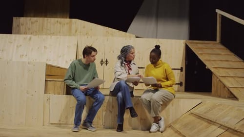 Female Director Discussing Script with Actors on Theatre Stage