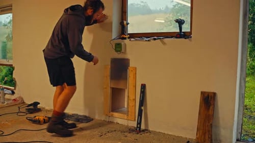 Un homme appuie sur un bouton pour que le couvercle coulissant automatique se déplace vers le bas au-dessus d'une petite ouverture murale