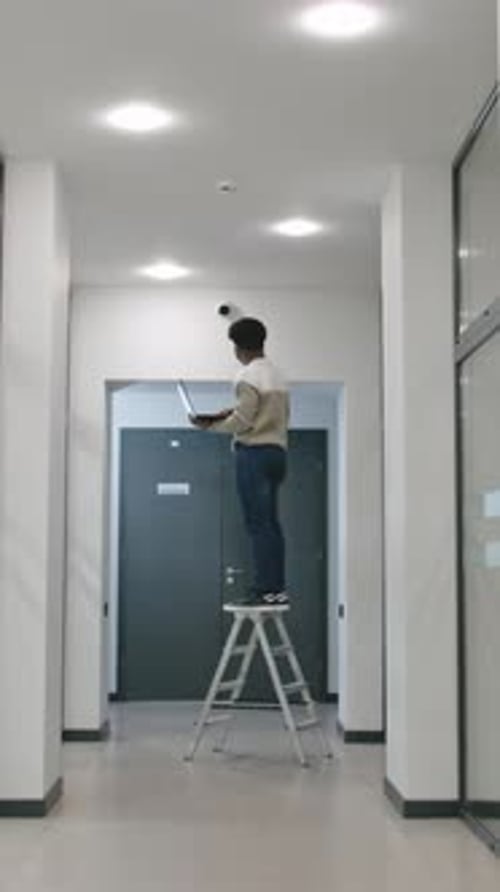 Man Stays on Ladder and Checks CCTV Cameras in Computer Program