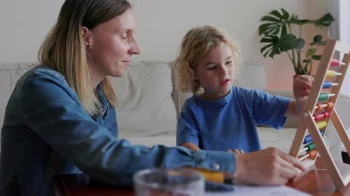 Educación en casa: madre e hijo estudian matemáticas para hacer los deberes del jardín de infantes con ábaco - Familia