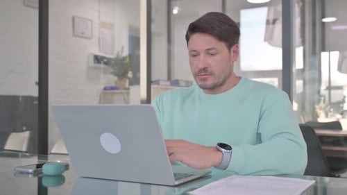 Man Working on a Laptop at an Office Desk