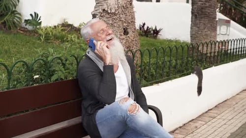 Senior Man with Beard Talking on Phone on Bench