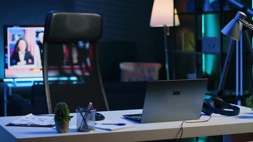 Dimly Lit Apartment with Office Desk in Front of Smart TV Displaying News Program