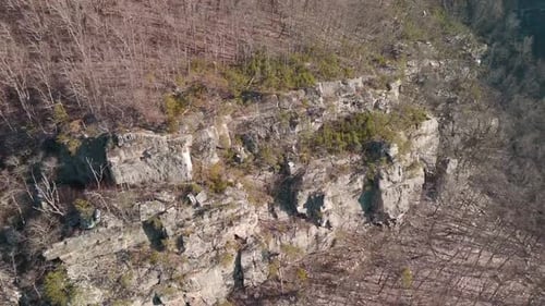 Aerial drone footage captures an expansive, arid rocky landscape under bright sun, with rugged terra