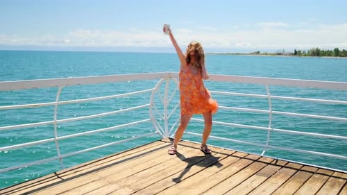 Woman Dancing on Pier Overlooking Turquoise Sea