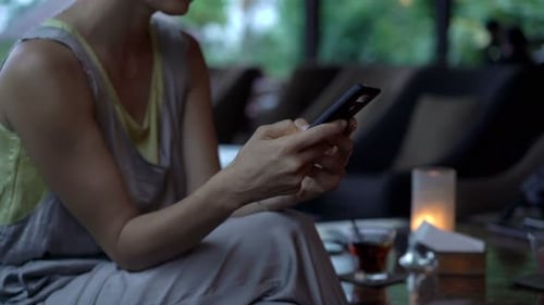 Young woman texting on smartphone relaxing in a cafe using mobile technology