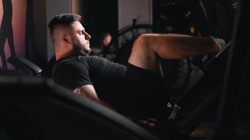 Man Exercising on Leg Press Machine in Gym