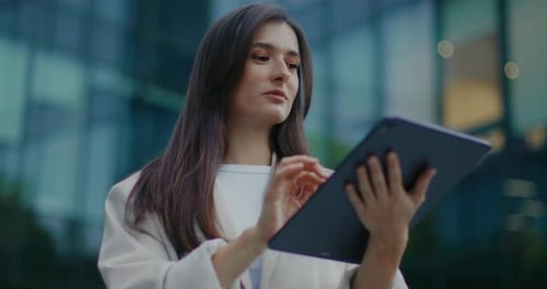 Woman Using Tablet Outside Glass Corporate Building