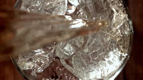 Clear Liquid Being Poured onto Ice in Glass