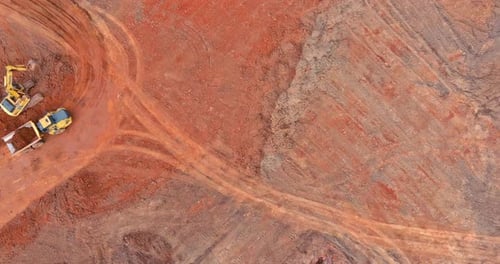Construction Site Shows Heavy Machinery Working on Red Earth in a Large Open Area