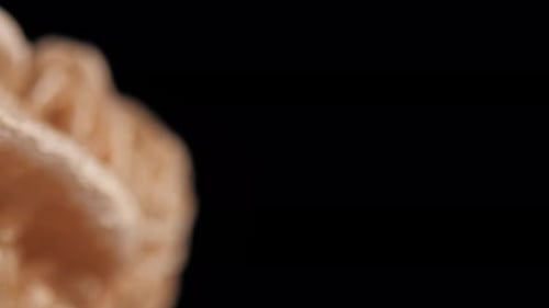 Cinematic pan of a sand-colored desert rose selenite against a dark background. Macro videography re