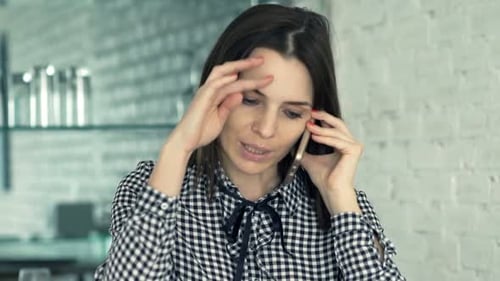 Woman talking on phone while using laptop