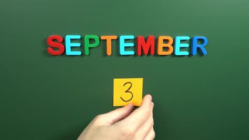 Hand sticking a sticker 3 September calendar day on school board. 3 date of September. Third day
