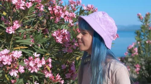 Young Person Smelling Pink Flowers by the Ocean