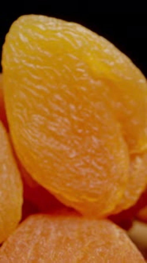 Vertical video. Dried Apricots Are Spread Out in a Large Pile on the Table. Dolly slider macro.