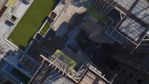 Vídeo aéreo de trabajadores vertiendo concreto y operando grúas en una concurrida obra de construcción capturado desde